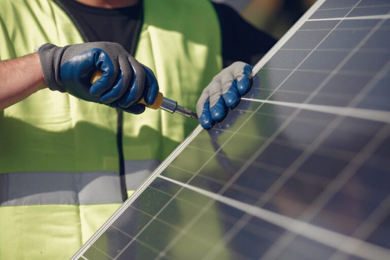 Eine Person arbeitet an einer Photovoltaik-Anlage mit einem Werkzeug.