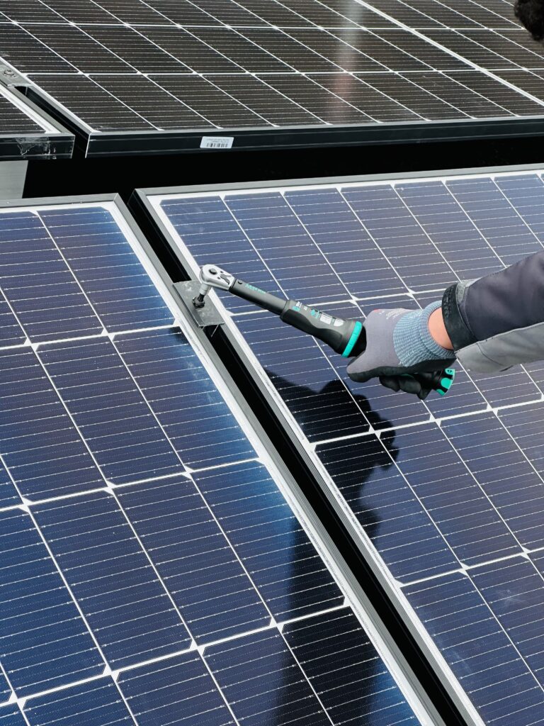 Eine Person arbeitet an einer Solarpaneele mit einem Werkzeug. Effiziente Wartung für maximale Energieerzeugung.