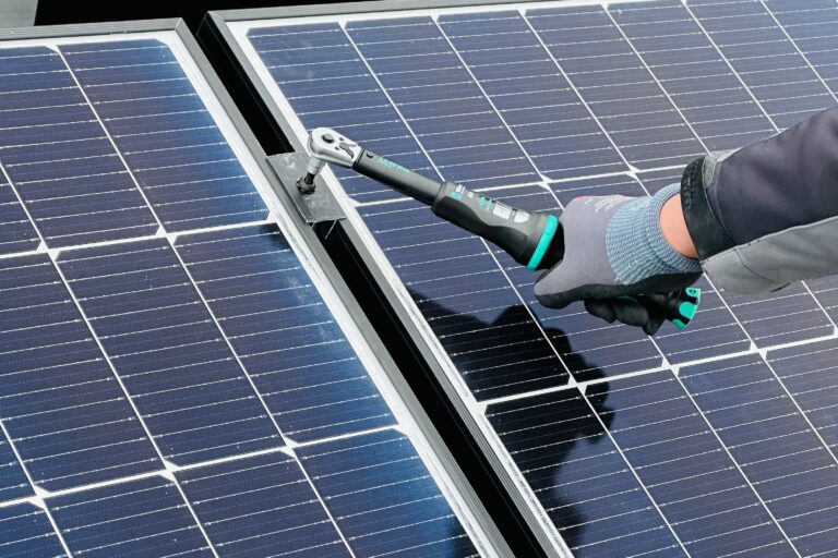 Eine Person arbeitet an einer Solarpaneele mit einem Werkzeug. Effiziente Wartung für maximale Energieerzeugung.